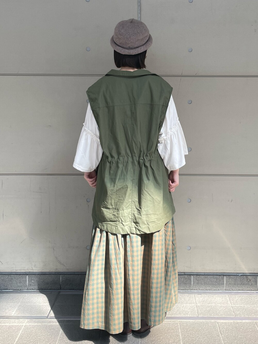 ブラウン系のブーツ、グリーン系のベスト、ホワイト系のTシャツ/カットソーを着用したレディースの夏コーディネートの2枚目の写真