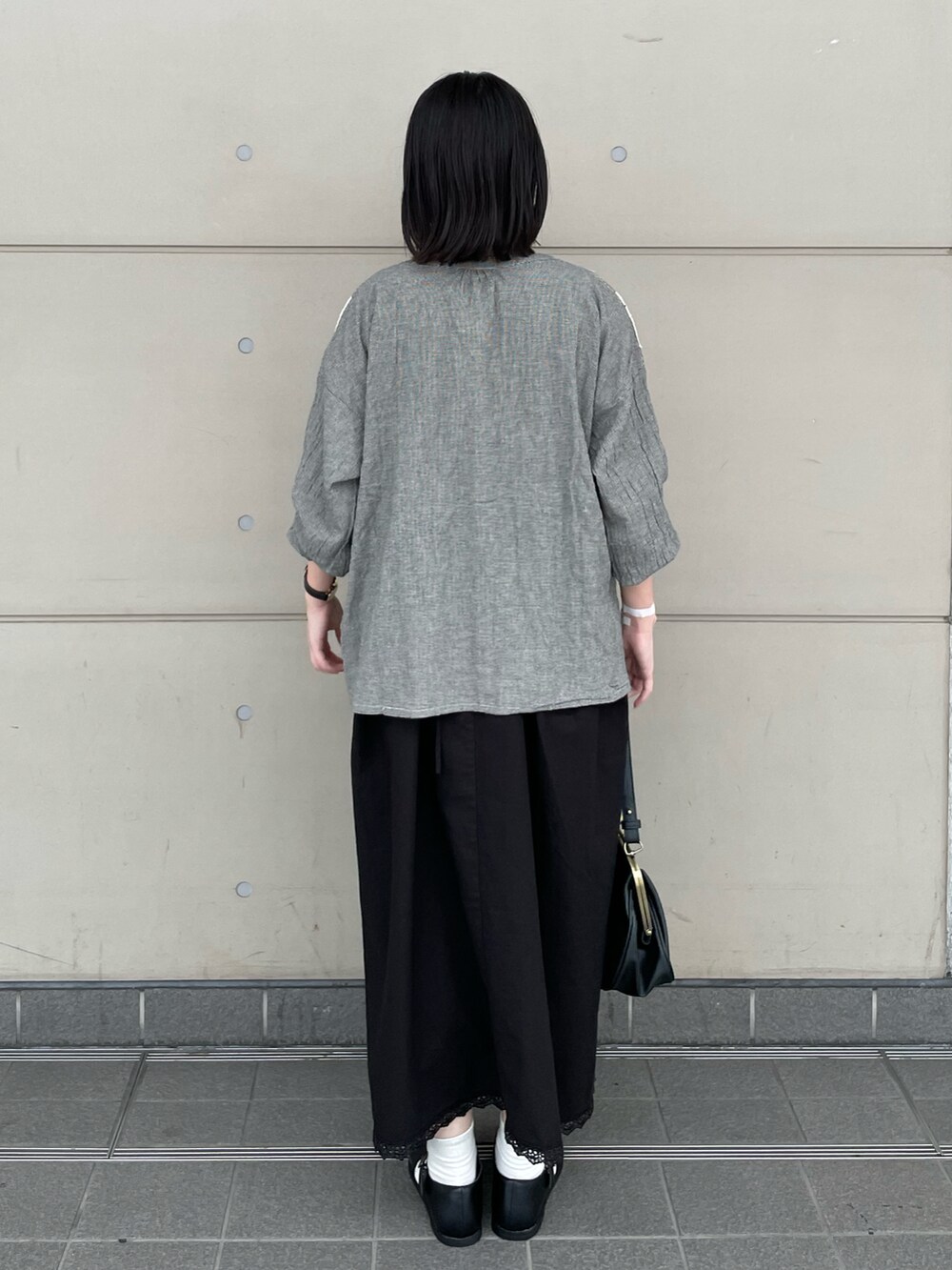 ブラック系のハンドバッグ、ブラック系のドレスシューズ、グレー系のシャツ/ブラウスを着用したレディースの秋コーディネートの3枚目の写真