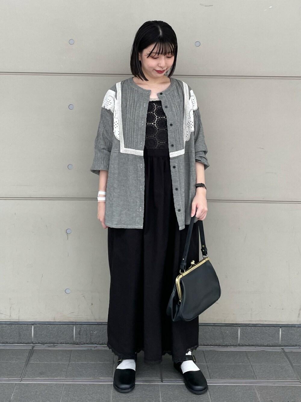 ブラック系のハンドバッグ、ブラック系のドレスシューズ、グレー系のシャツ/ブラウスを着用したレディースの秋コーディネートの2枚目の写真