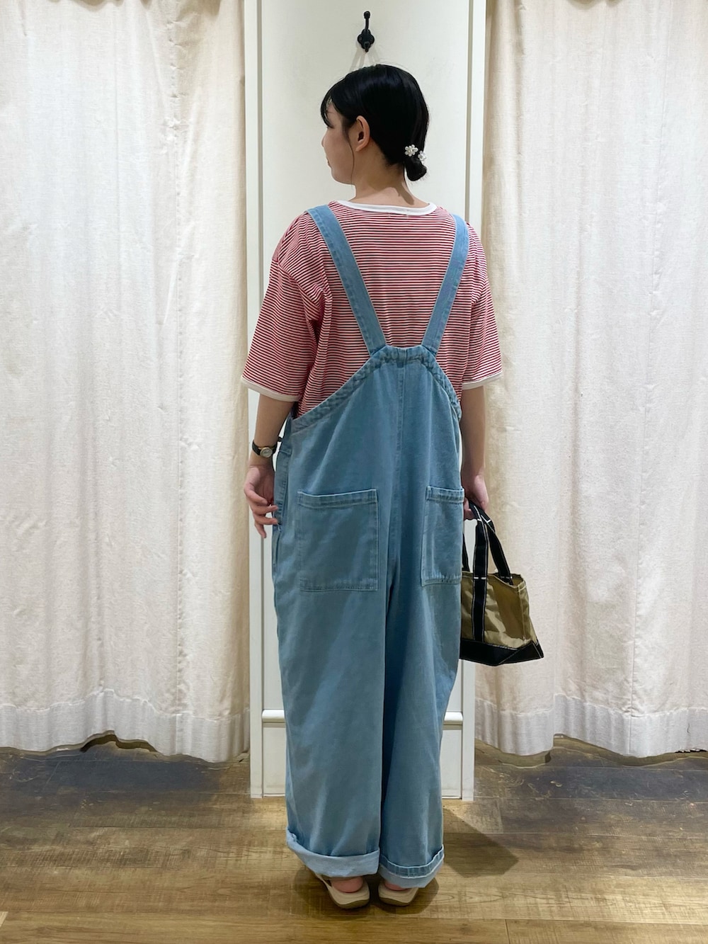 レッド系のTシャツ/カットソー、ブルー系のサロペット/オーバーオール、ベージュ系のハンドバッグを着用したレディースの冬コーディネートの2枚目の写真