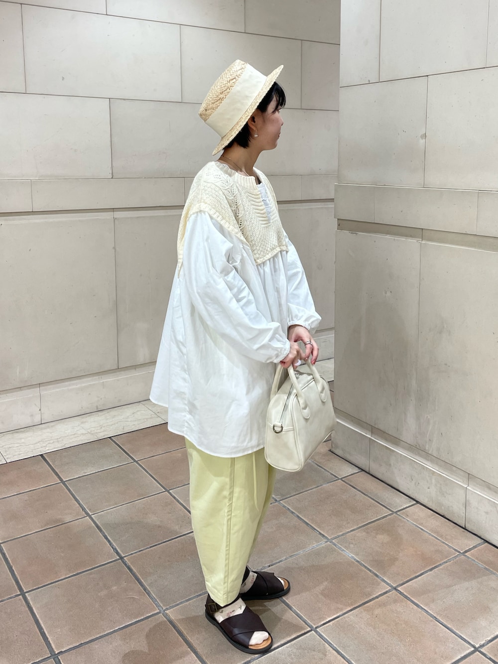 ホワイト系のショルダーバッグ、ブラウン系のサンダル、イエロー系のその他パンツを着用したレディースの春コーディネートの2枚目の写真