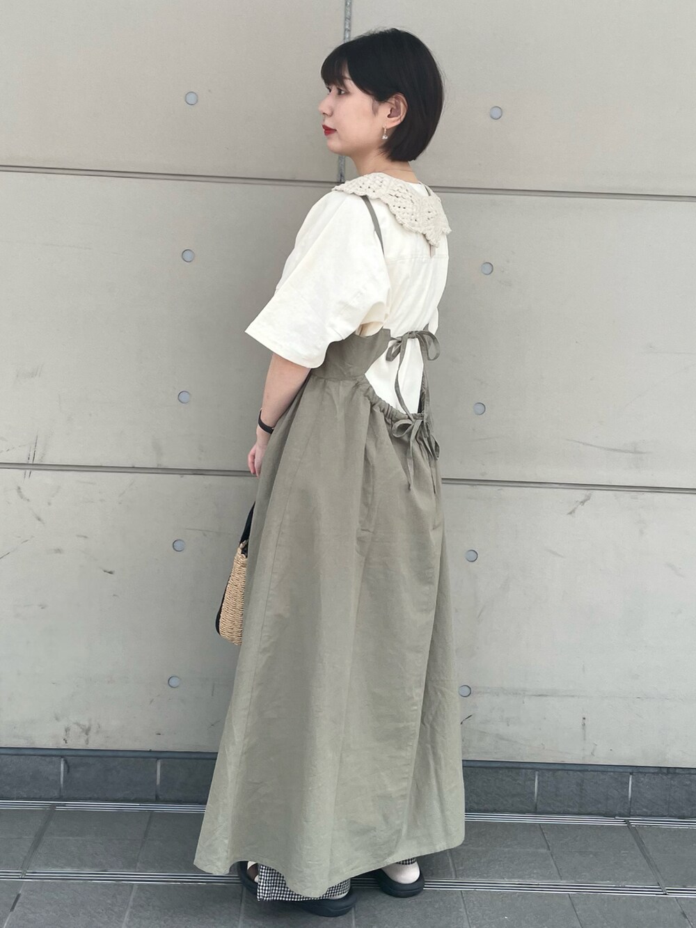 ブラック系のハンドバッグ、ホワイト系のTシャツ/カットソー、グリーン系のワンピースを着用したレディースの夏コーディネートの2枚目の写真