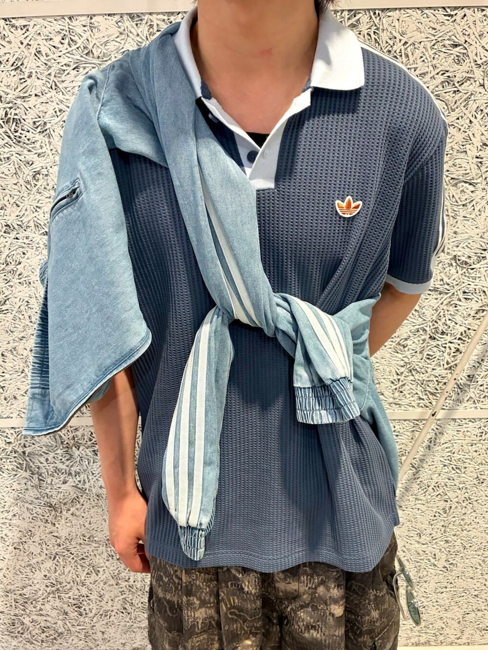 ブルー系のポロシャツ、グレー系のカーゴパンツ、グレー系のスニーカーを着用したメンズの夏コーディネートの2枚目の写真