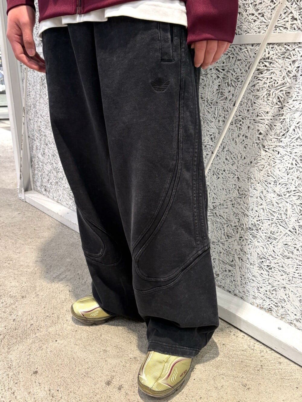 レッド系のジャージ、ブラック系のその他パンツ、ゴールド系のシューズを着用したメンズの春コーディネートの3枚目の写真