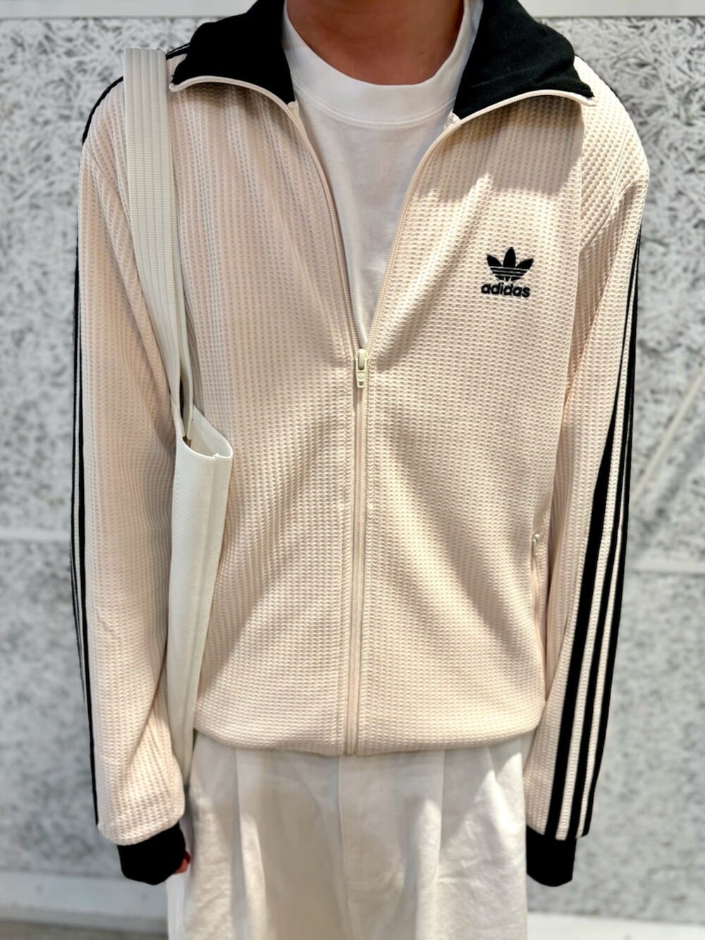 ホワイト系のジャージ、ホワイト系のトートバッグ、ブラック系のスニーカーを着用したメンズの夏コーディネートの2枚目の写真