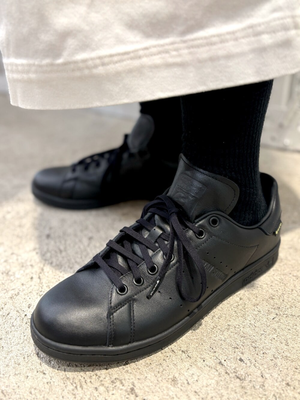 ホワイト系のジャージ、ホワイト系のトートバッグ、ブラック系のスニーカーを着用したメンズの夏コーディネートの4枚目の写真