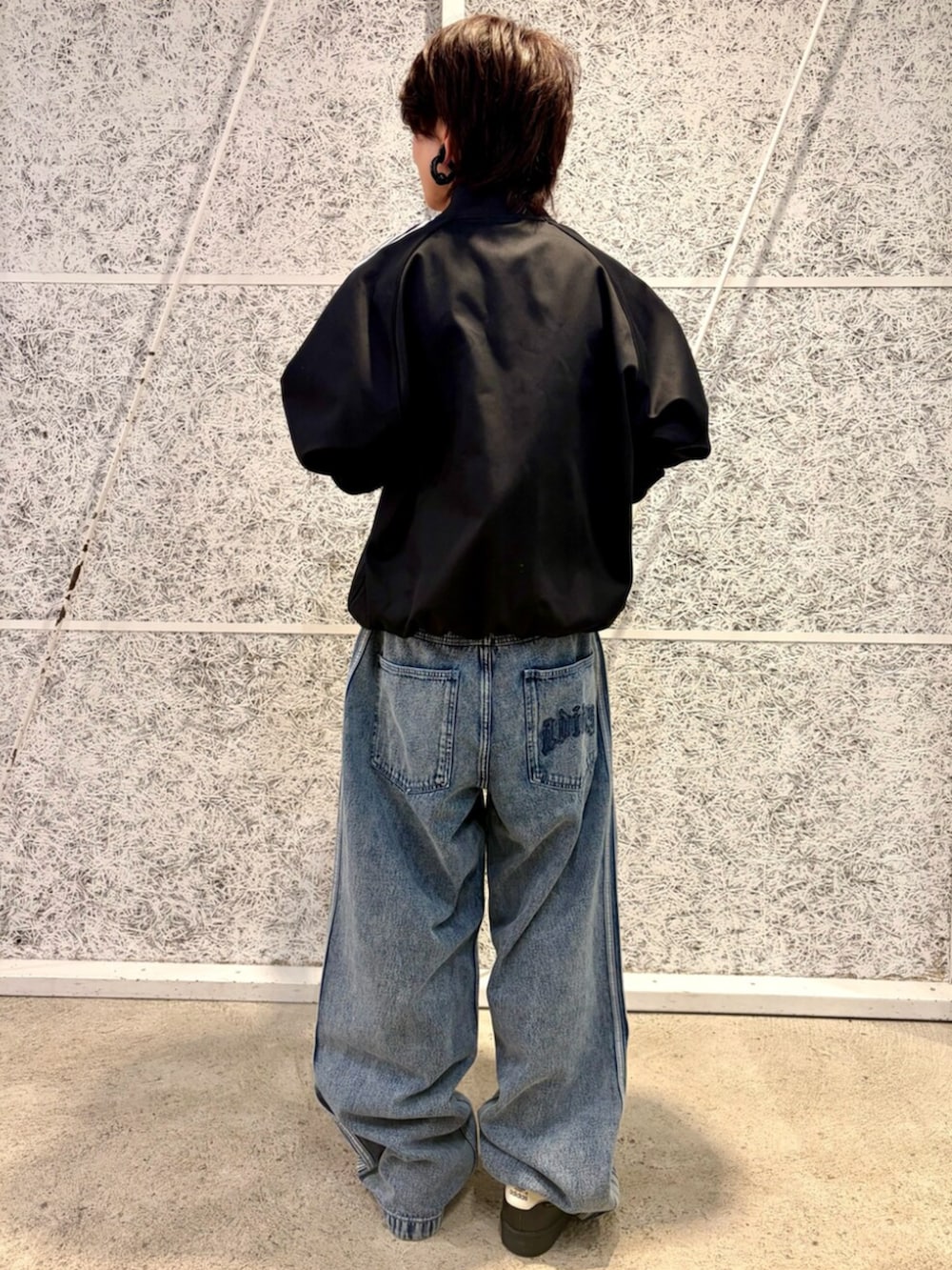 ブラック系のジャージ、ブルー系のデニムパンツ、ブラック系のスニーカーを着用したメンズの秋コーディネートの2枚目の写真