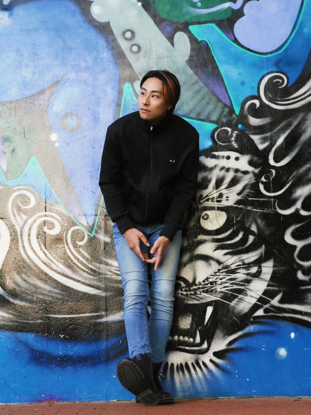 ブラック系のジャージ、ブルー系のデニムパンツ、ブラック系のブーツを着用したメンズの春コーディネートの3枚目の写真