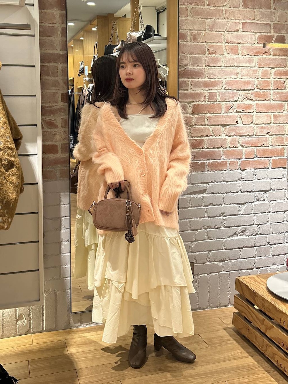 ベージュ系のキャミソール、ホワイト系のスカート、ブラウン系のボストンバッグを着用したレディースの秋コーディネートの7枚目の写真