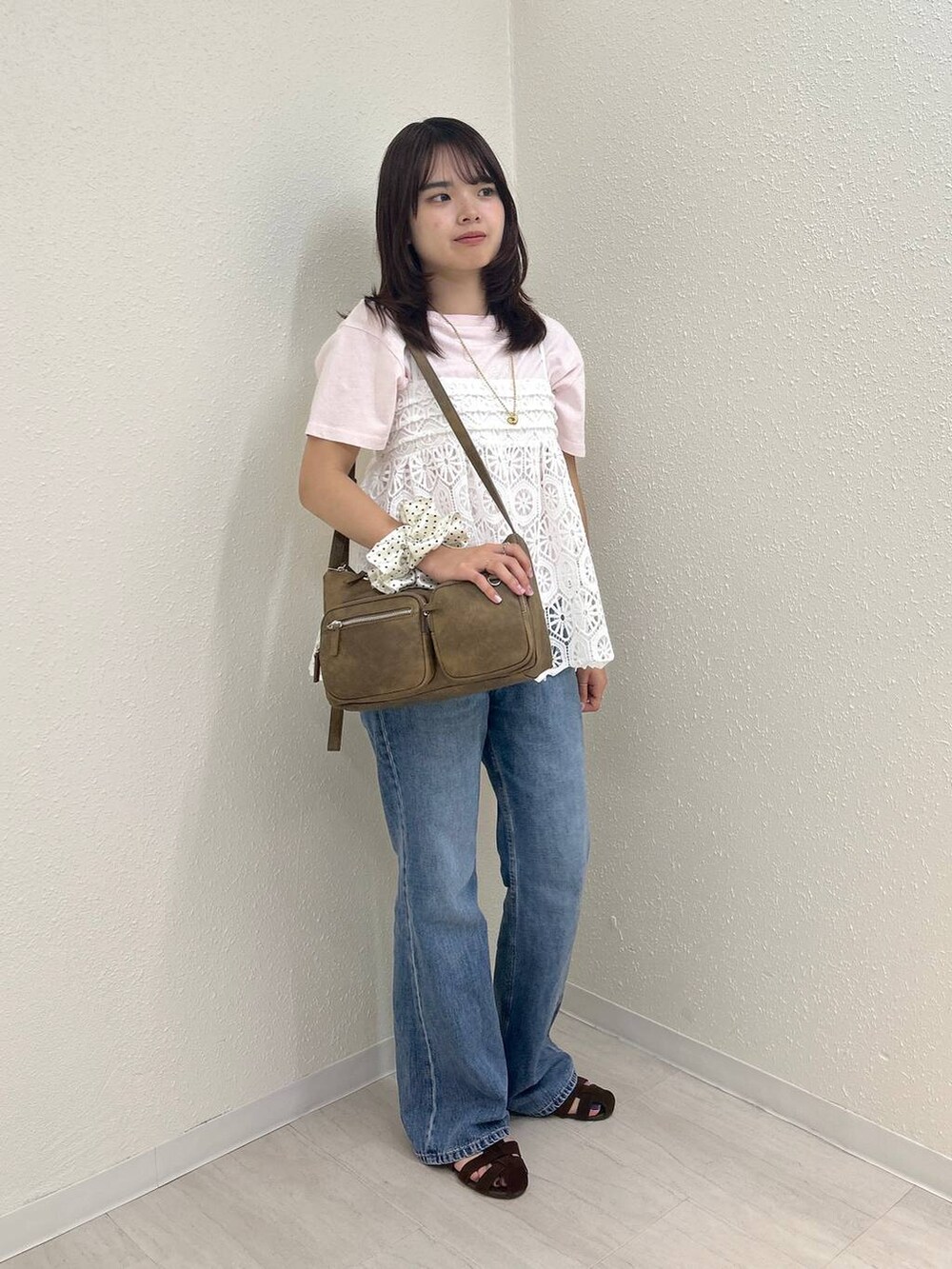 ホワイト系のキャミソール、ブラウン系のサンダル、ブルー系のデニムパンツを着用したレディースの夏コーディネートの4枚目の写真