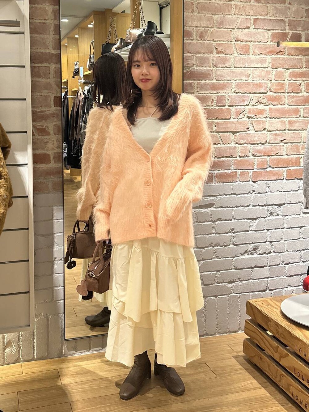 ベージュ系のキャミソール、ホワイト系のスカート、ブラウン系のボストンバッグを着用したレディースの秋コーディネートの6枚目の写真