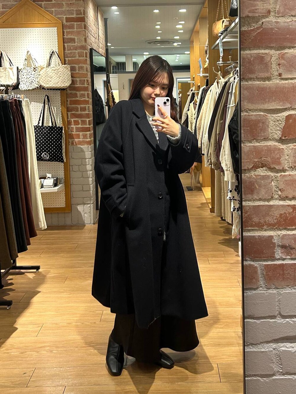 ブルー系のチェスターコート、ブラック系のスカート、ブラック系のブーツを着用したレディースの冬コーディネートの2枚目の写真