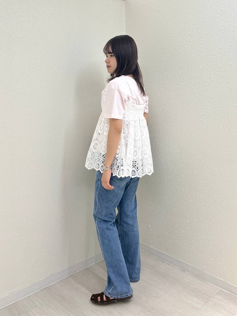 ホワイト系のキャミソール、ブラウン系のサンダル、ブルー系のデニムパンツを着用したレディースの夏コーディネートの2枚目の写真