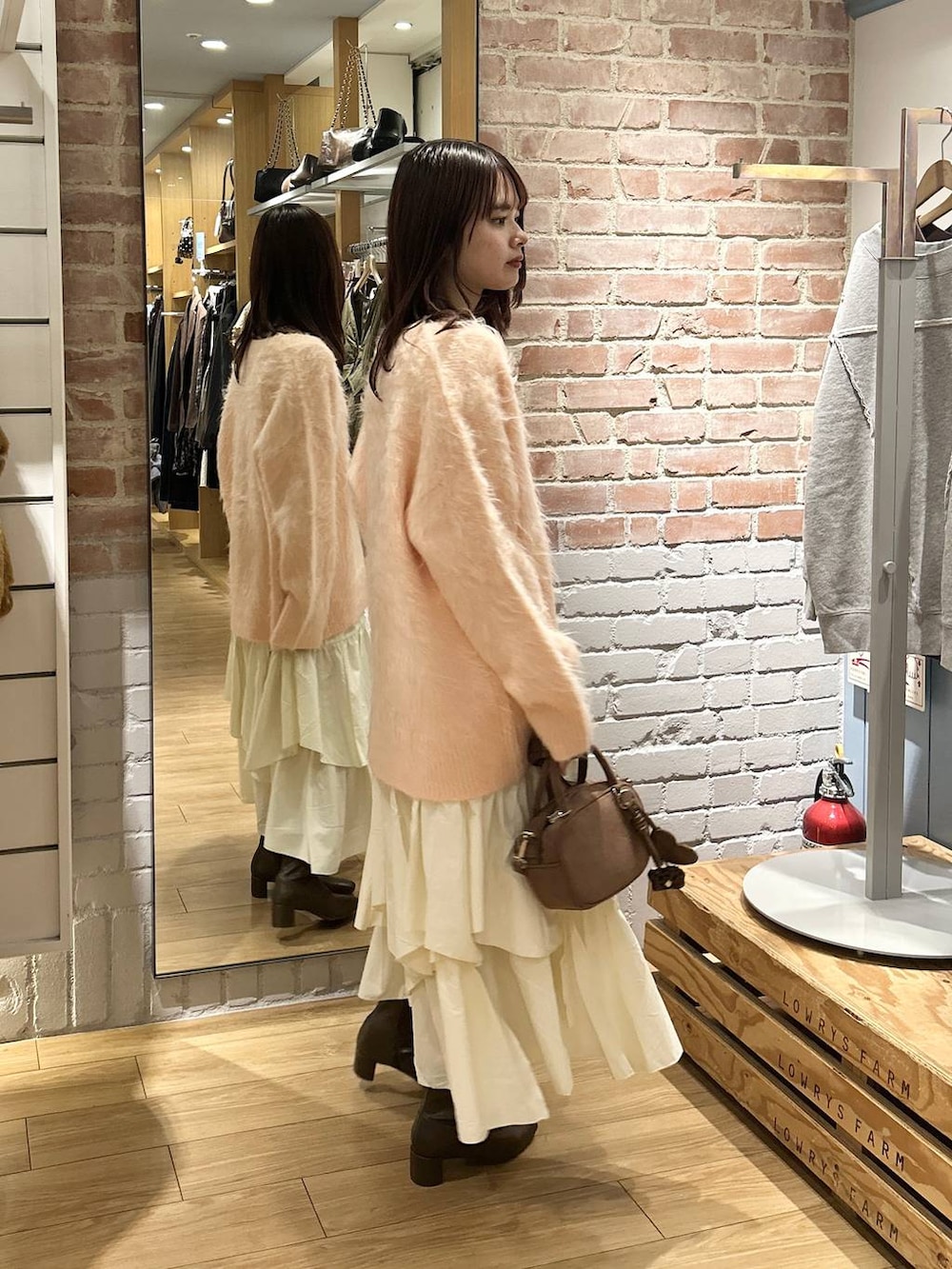 ベージュ系のキャミソール、ホワイト系のスカート、ブラウン系のボストンバッグを着用したレディースの秋コーディネートの3枚目の写真