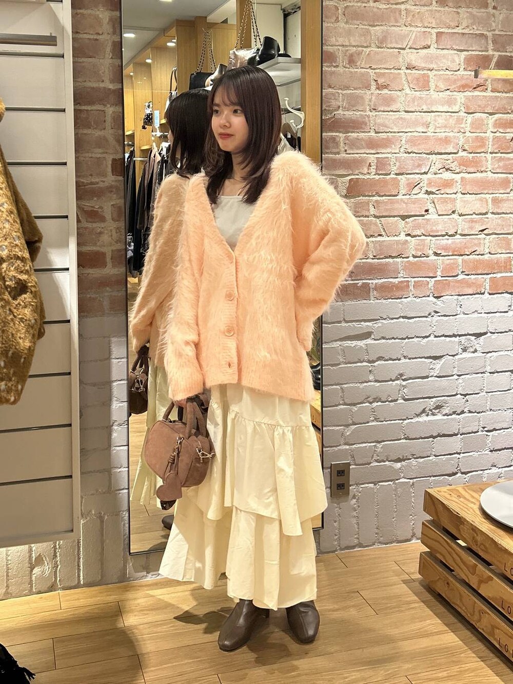 ベージュ系のキャミソール、ホワイト系のスカート、ブラウン系のボストンバッグを着用したレディースの秋コーディネートの5枚目の写真