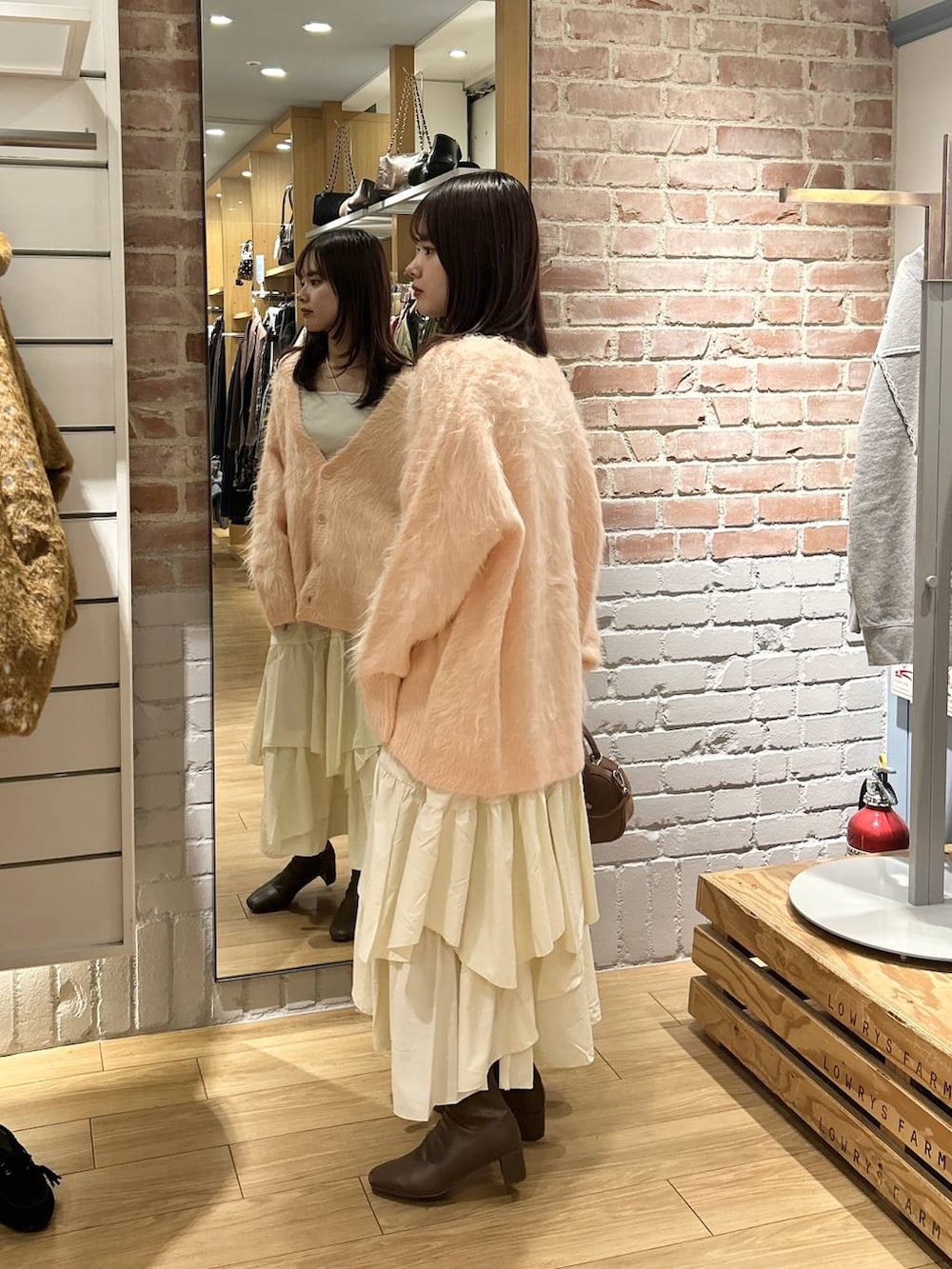 ベージュ系のキャミソール、ホワイト系のスカート、ブラウン系のボストンバッグを着用したレディースの秋コーディネートの2枚目の写真