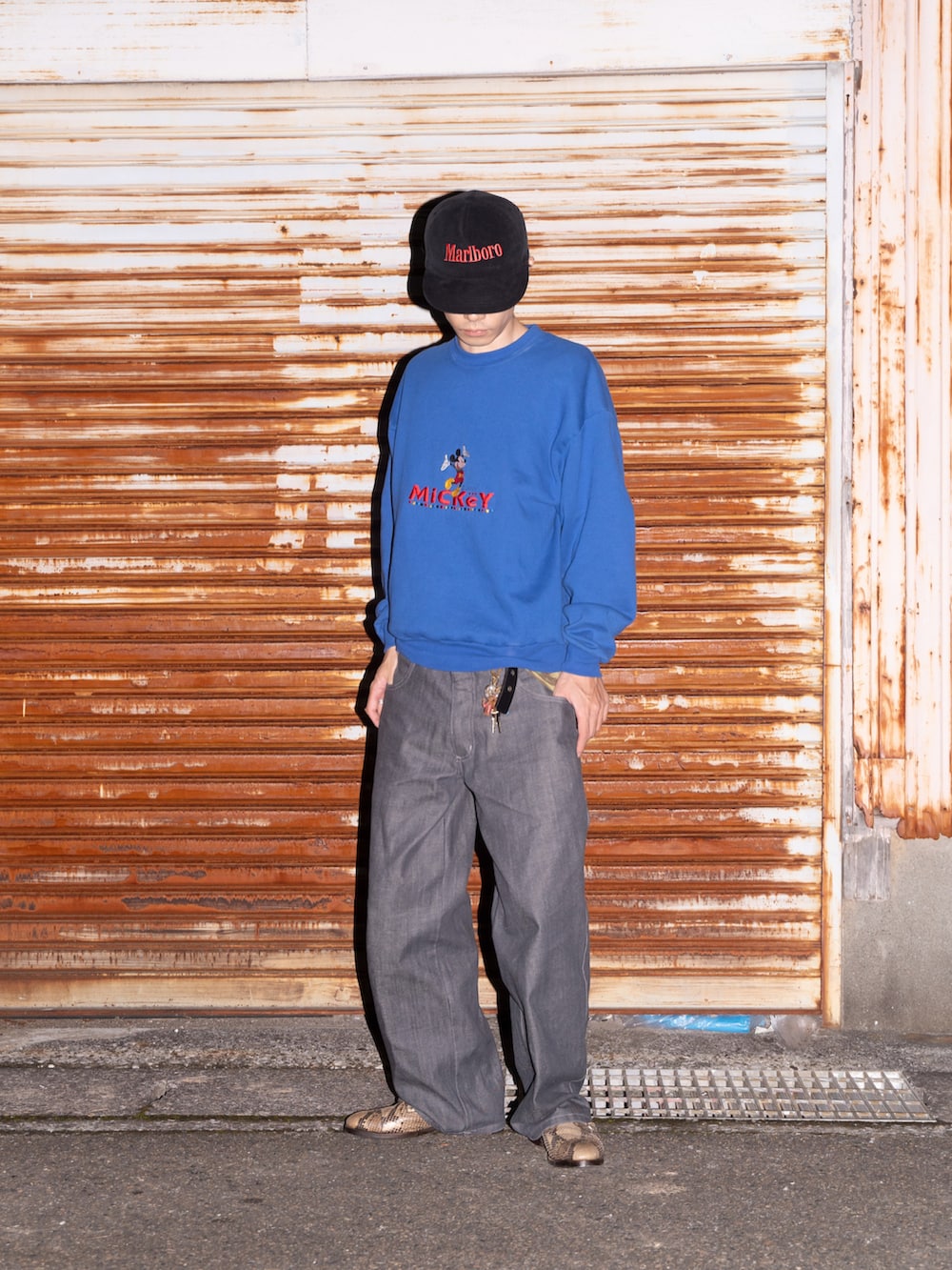 ブルー系のスウェット、ブルー系のデニムパンツ、ベージュ系のドレスシューズを着用したメンズの秋コーディネートの3枚目の写真