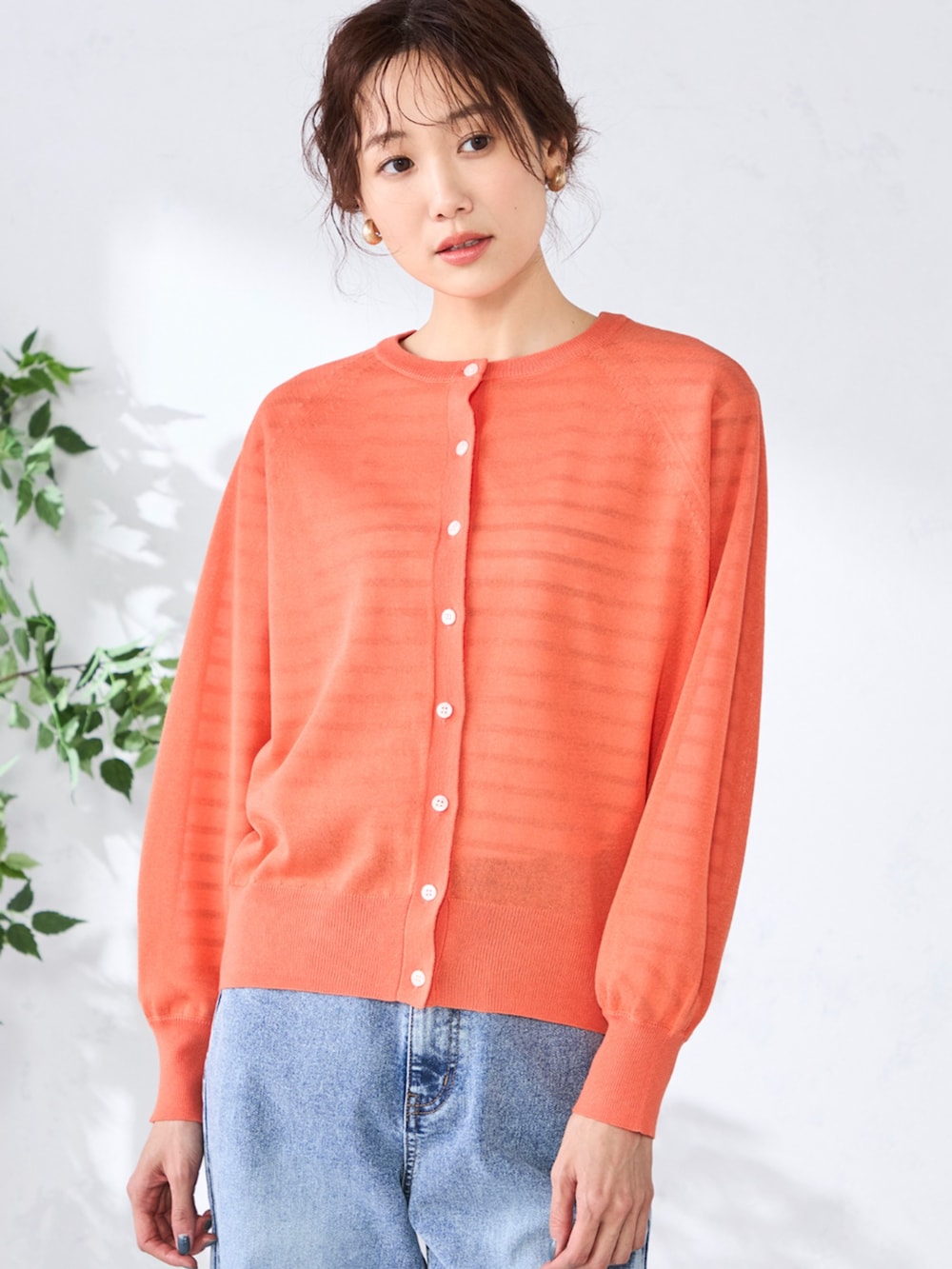 ブルー系のデニムパンツ、ベージュ系のTシャツ/カットソー、オレンジ系のカーディガン/ボレロを着用したレディースの春コーディネートの2枚目の写真