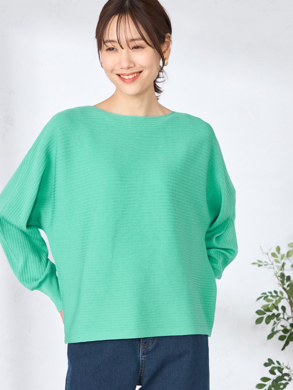 ブルー系のデニムパンツ、グリーン系のニット/セーターを着用したレディースの春コーディネートの2枚目の写真