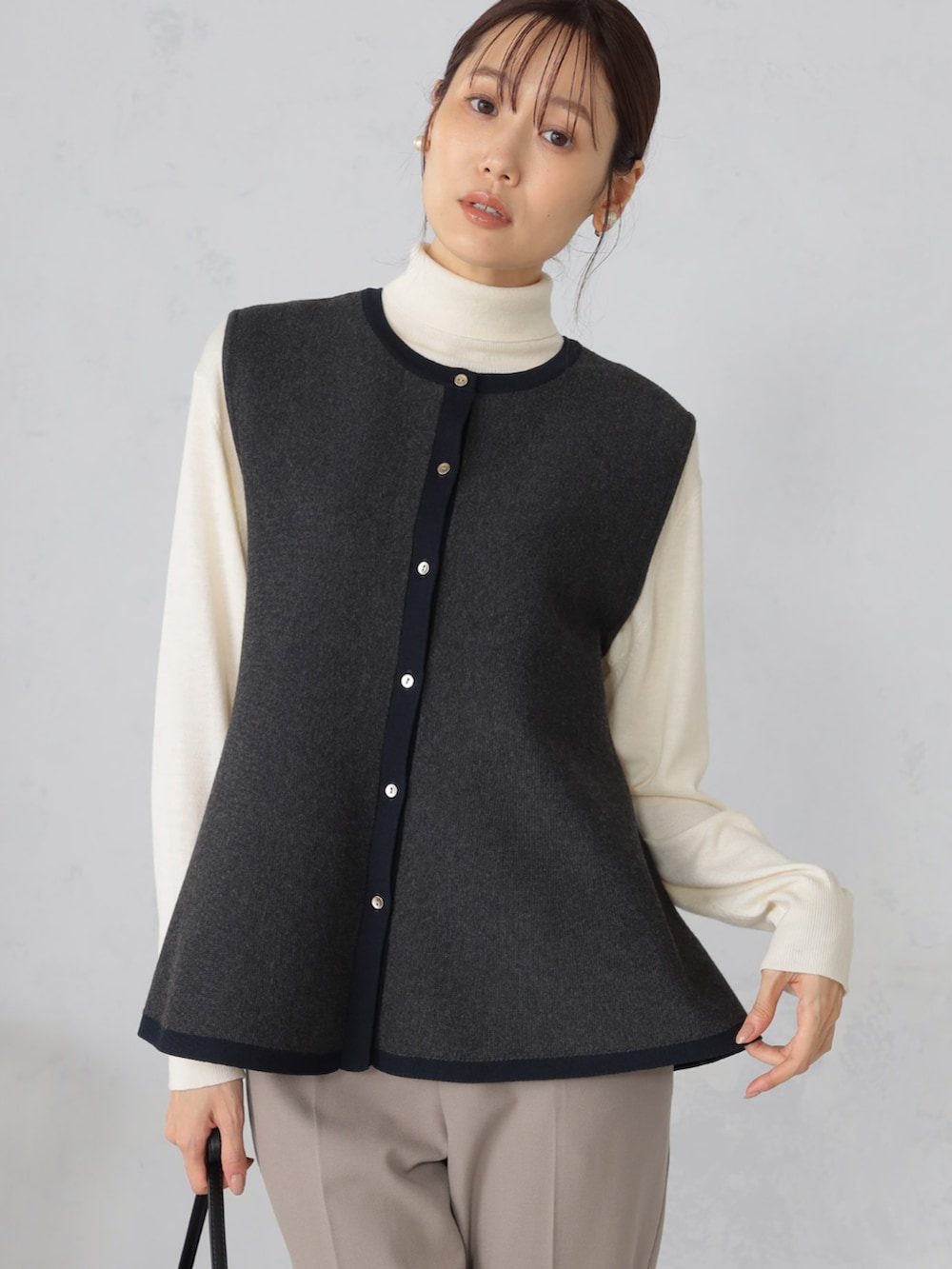 グレー系のベスト、ブラウン系のその他パンツ、ベージュ系のニット/セーターを着用したレディースの秋コーディネートの2枚目の写真