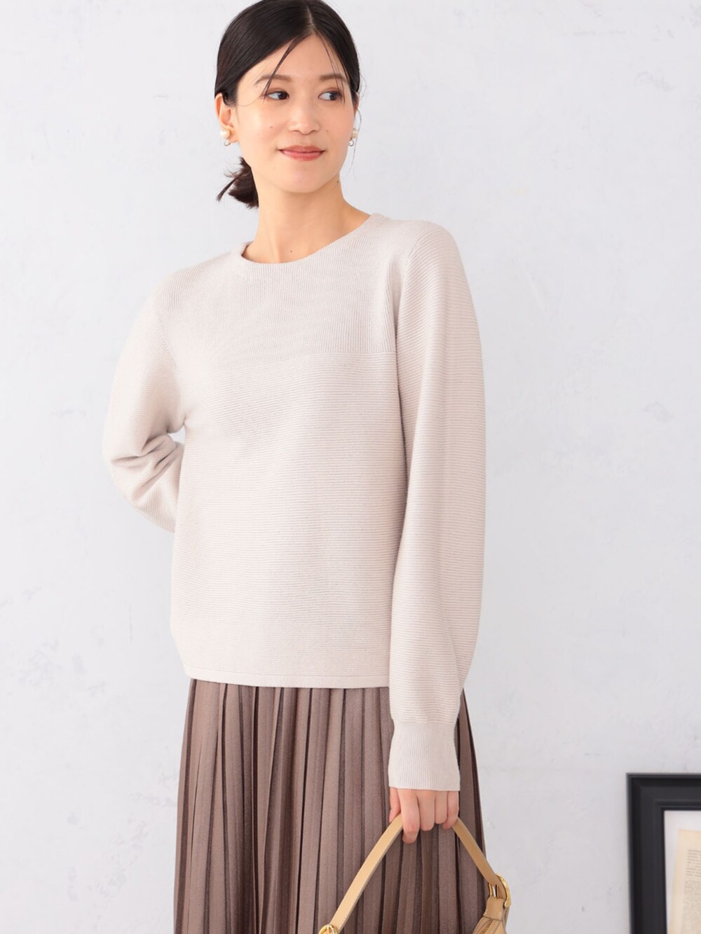 ブラウン系のスカート、グレー系のニット/セーターを着用したレディースの秋コーディネートの2枚目の写真