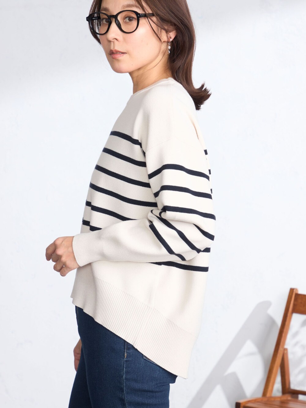 ベージュ系のステンカラーコート、ブルー系のニット/セーターを着用したレディースの春コーディネートの4枚目の写真