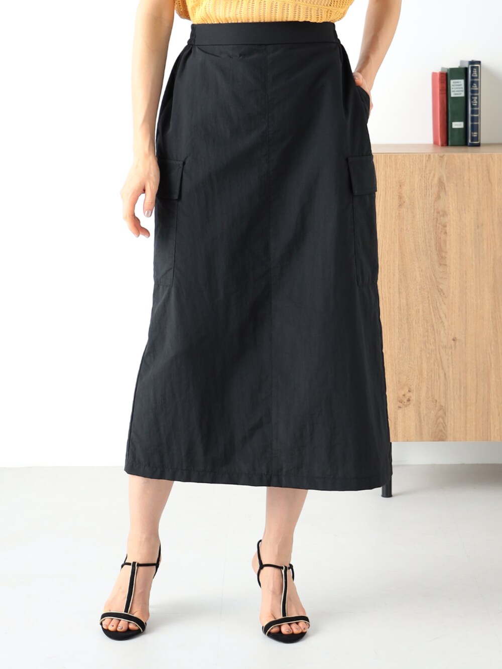 イエロー系のニット/セーター、ブラック系のスカートを着用したレディースの夏コーディネートの3枚目の写真