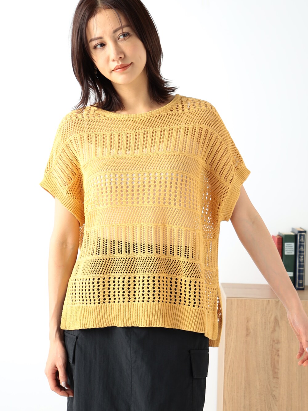 イエロー系のニット/セーター、ブラック系のスカートを着用したレディースの夏コーディネートの2枚目の写真