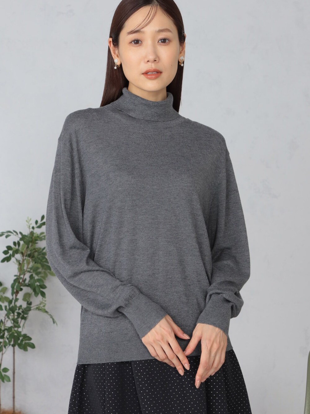 グレー系のニット/セーター、ブラック系のスカートを着用したレディースの秋コーディネートの2枚目の写真