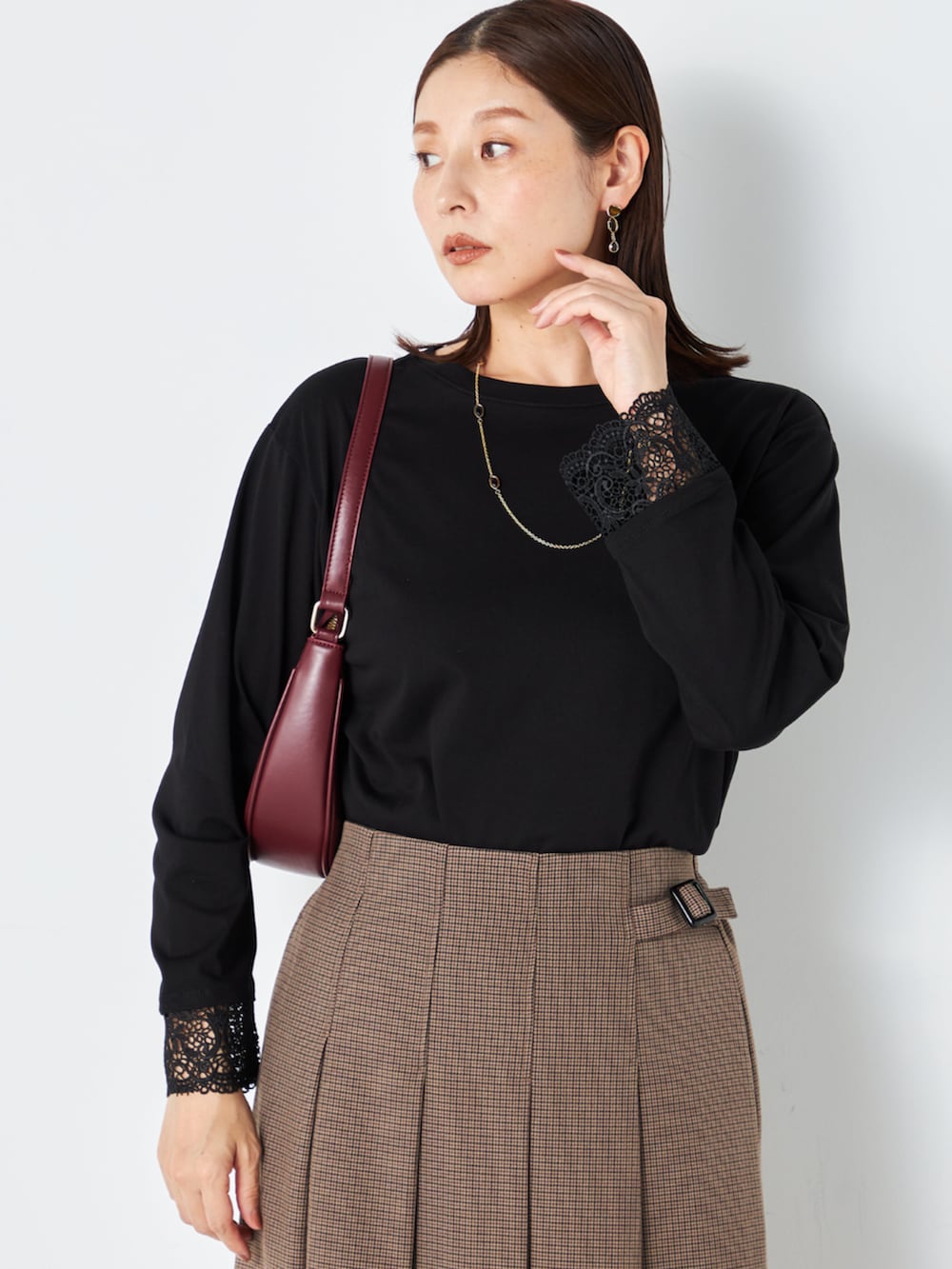 ブラウン系のスカート、ブラック系のTシャツ/カットソーを着用したレディースの秋コーディネートの2枚目の写真