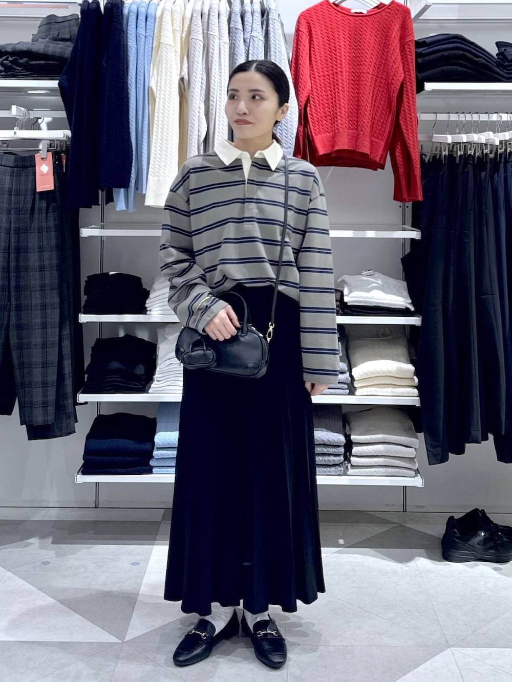 ブラック系のローファー、ブラック系のスカート、ブラック系のハンドバッグを着用したレディースの冬コーディネートの2枚目の写真