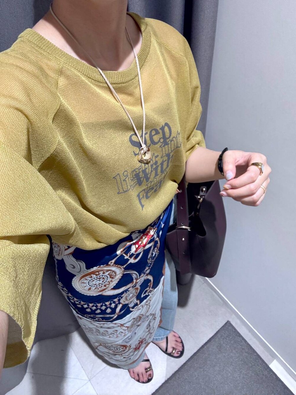 ブラウン系のショルダーバッグ、グリーン系のニット/セーター、ブルー系のデニムパンツを着用したレディースの夏コーディネートの4枚目の写真