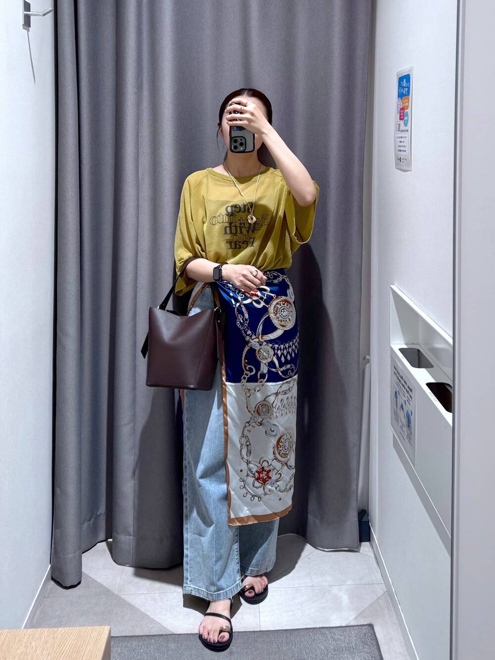 ブラウン系のショルダーバッグ、グリーン系のニット/セーター、ブルー系のデニムパンツを着用したレディースの夏コーディネートの2枚目の写真