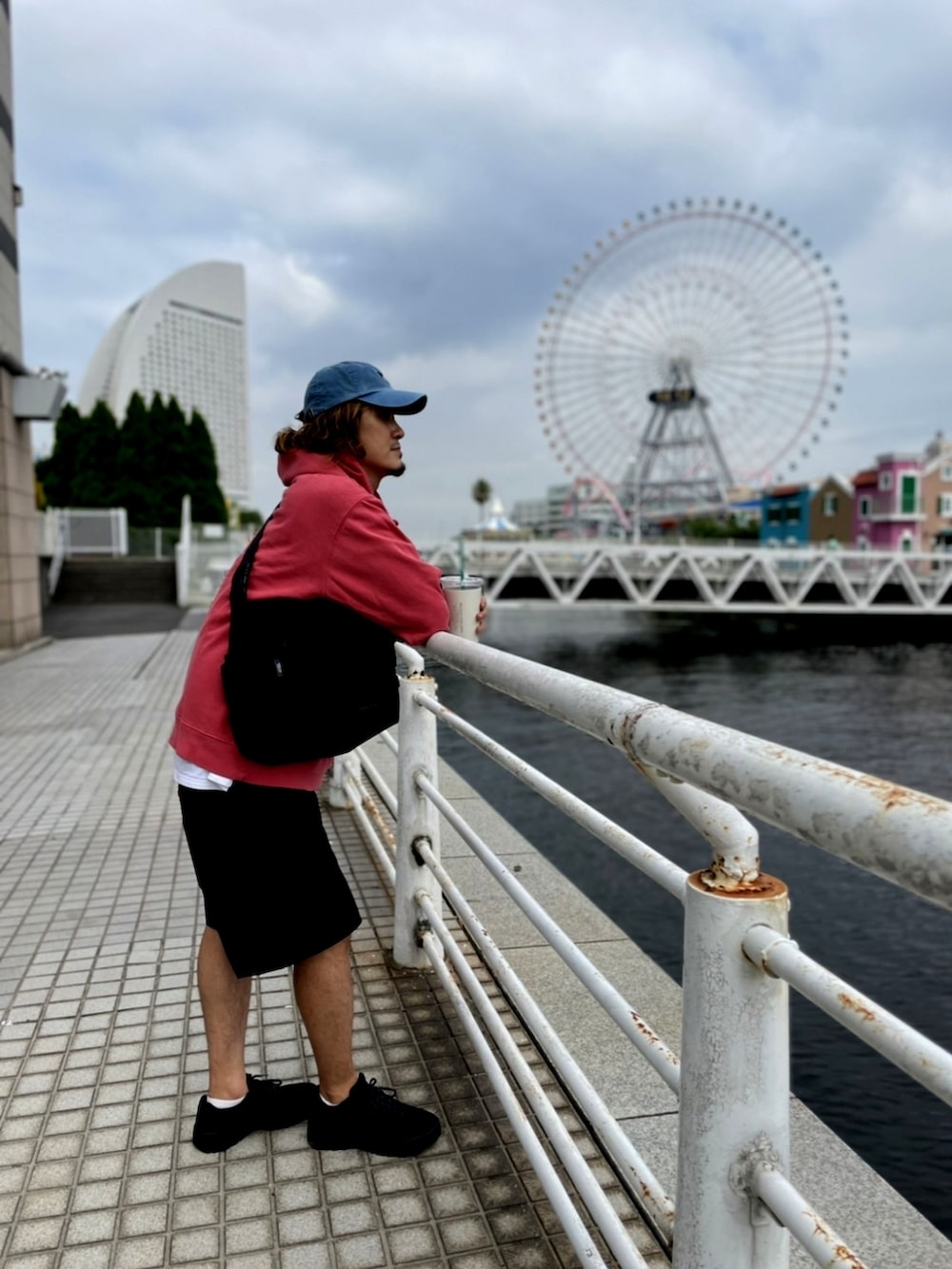 レッド系のパーカー、ブラック系のその他パンツ、ブラック系のメッセンジャーバッグを着用したメンズの夏コーディネートの2枚目の写真