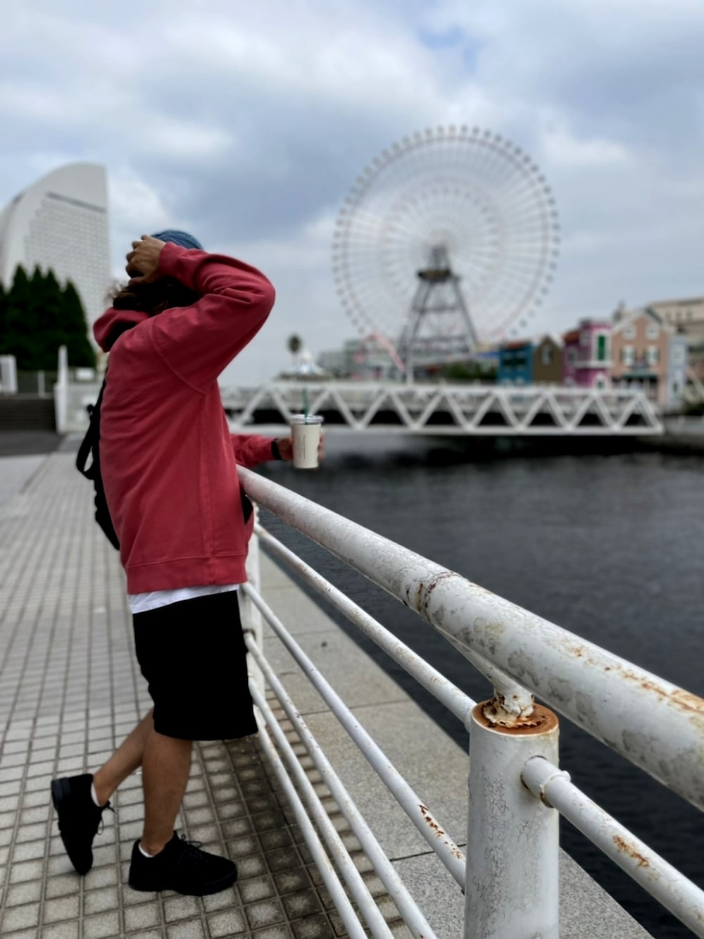 レッド系のパーカー、ブラック系のその他パンツ、ブラック系のメッセンジャーバッグを着用したメンズの夏コーディネートの3枚目の写真