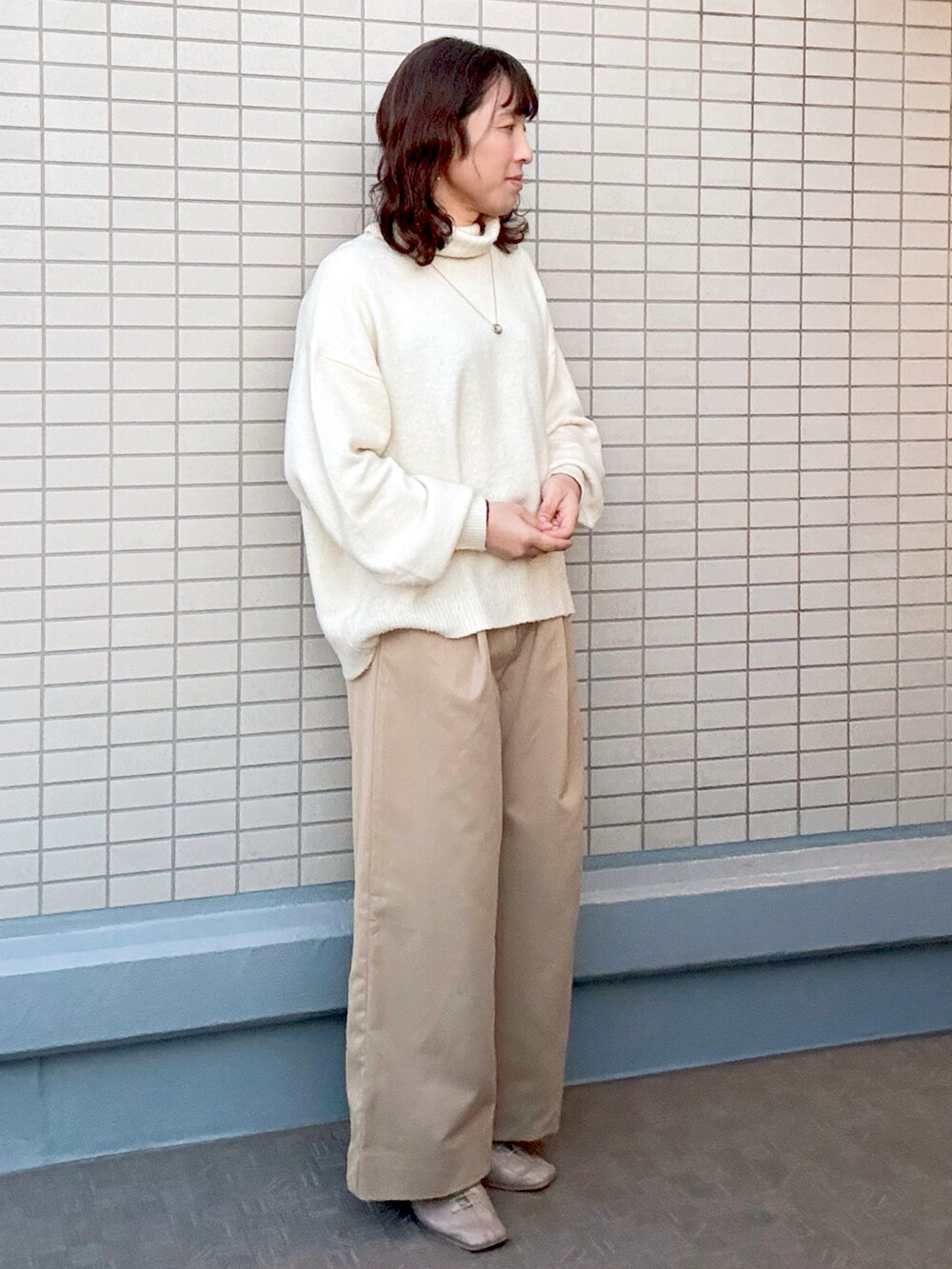 ベージュ系のチノパンツ、イエロー系のニット/セーター、ベージュ系のブーツを着用したレディースの冬コーディネートの2枚目の写真