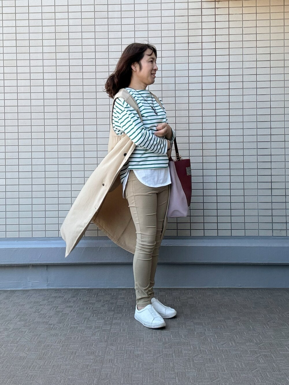 レッド系のトートバッグ、ベージュ系のその他パンツ、ホワイト系のスニーカーを着用したレディースの春コーディネートの2枚目の写真