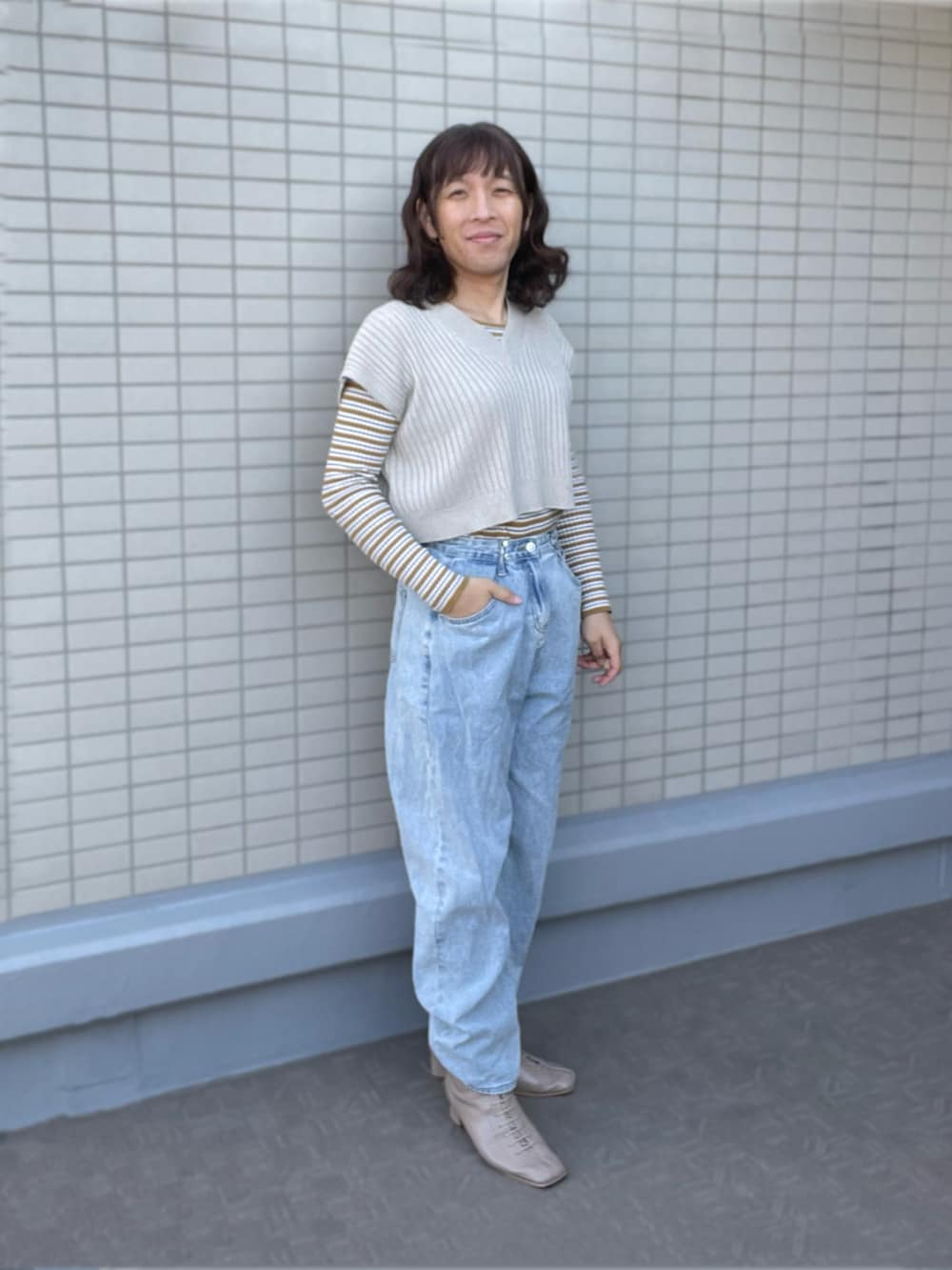 ブルー系のデニムパンツ、ベージュ系のブーツ、ホワイト系のベストを着用したレディースの冬コーディネートの2枚目の写真