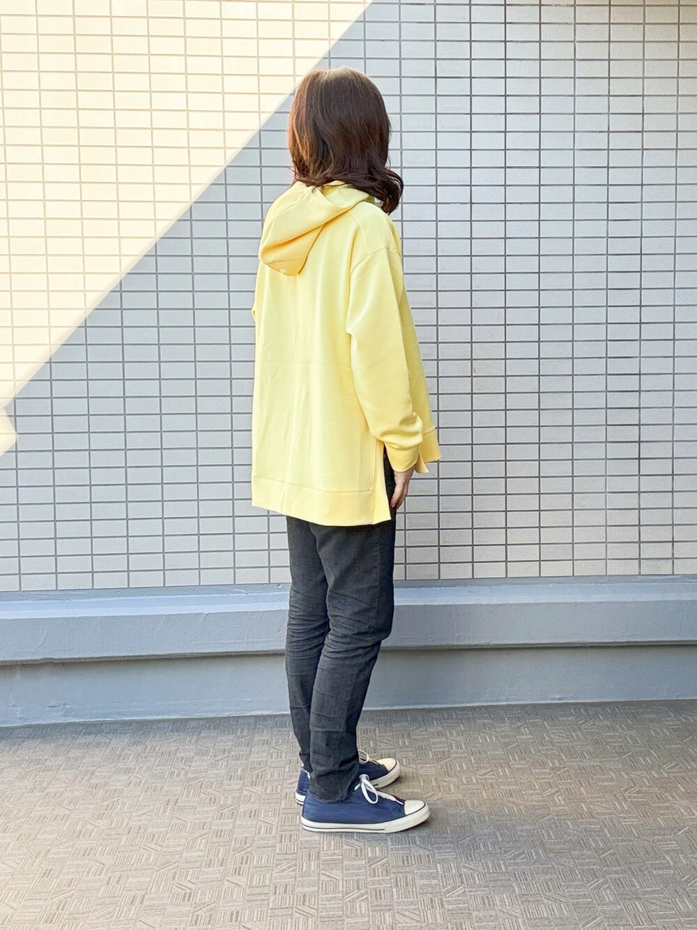ブラック系のデニムパンツ、イエロー系のスウェット、レッド系のトートバッグを着用したレディースの冬コーディネートの2枚目の写真