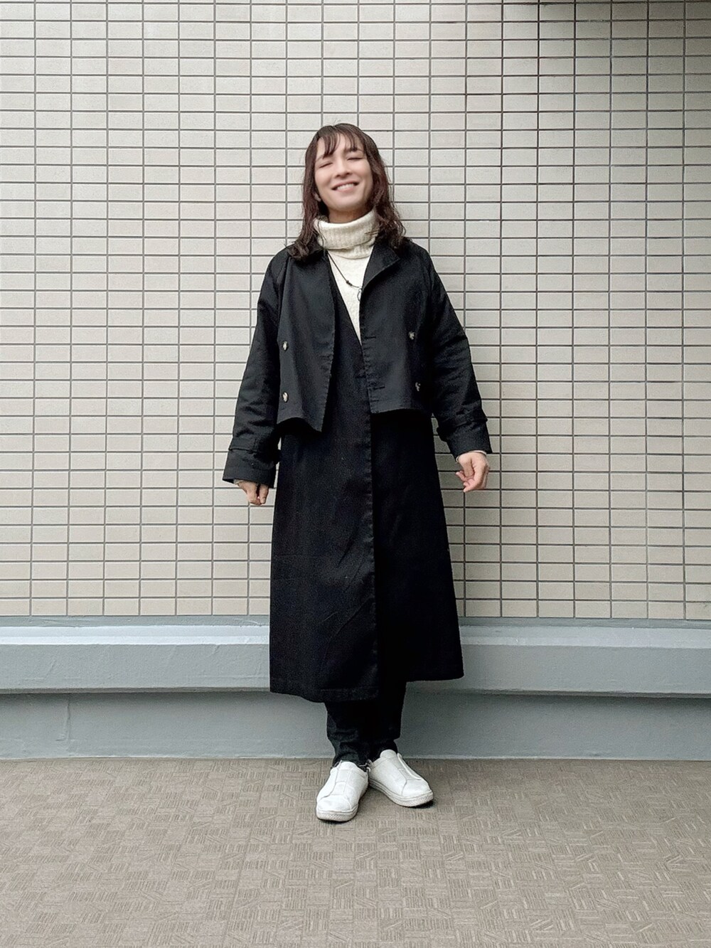 ブラック系のデニムパンツ、ホワイト系のスニーカー、ブラック系のトレンチコートを着用したレディースの春コーディネートの3枚目の写真