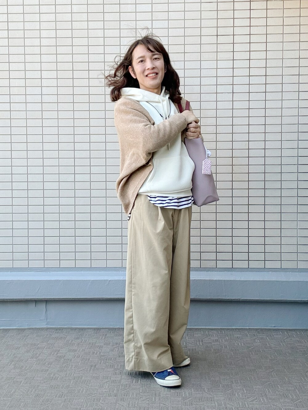 レッド系のトートバッグ、ベージュ系のチノパンツ、ホワイト系のパーカーを着用したレディースの冬コーディネートの2枚目の写真
