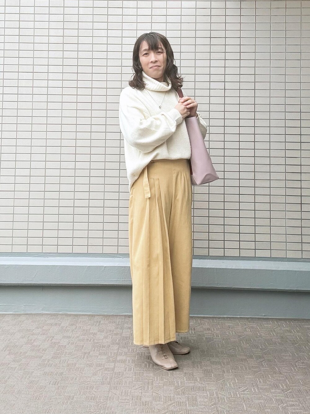 ベージュ系のブーツ、イエロー系のパンツ、レッド系のトートバッグを着用したレディースの冬コーディネートの2枚目の写真