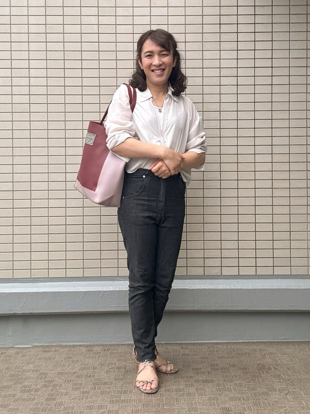 ホワイト系のトップス、ブラック系のデニムパンツ、レッド系のトートバッグを着用したレディースの春コーディネートの4枚目の写真