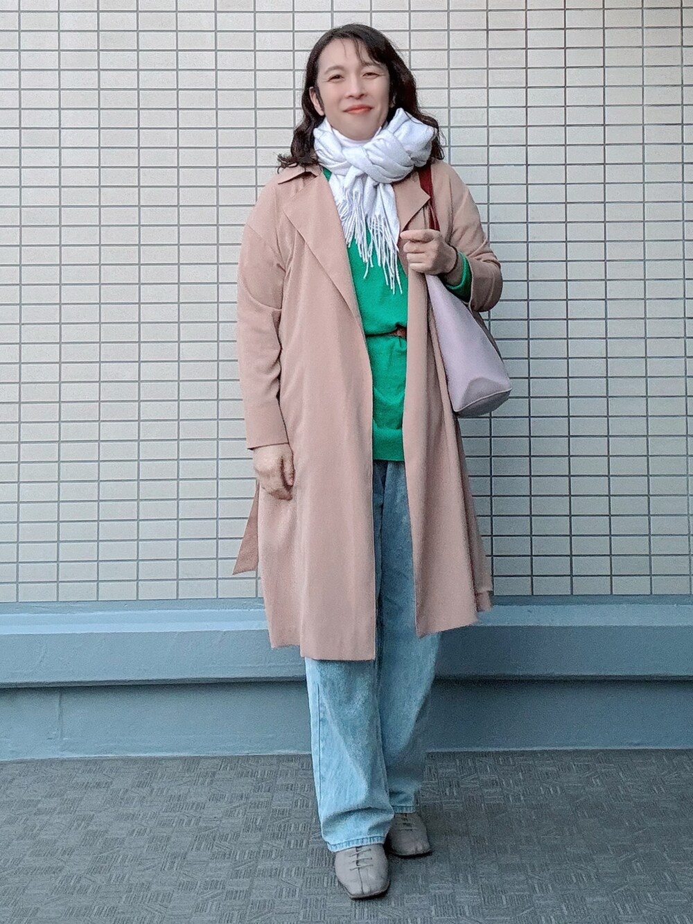 ブルー系のデニムパンツ、ベージュ系のブーツ、グリーン系のニット/セーターを着用したレディースの冬コーディネートの3枚目の写真