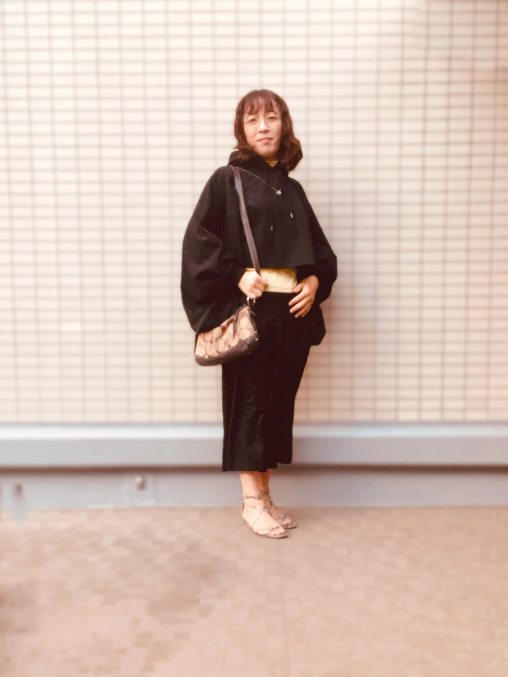 ブラック系のトップス、イエロー系のTシャツ/カットソー、ブラック系のパンツを着用したレディースの秋コーディネートの2枚目の写真