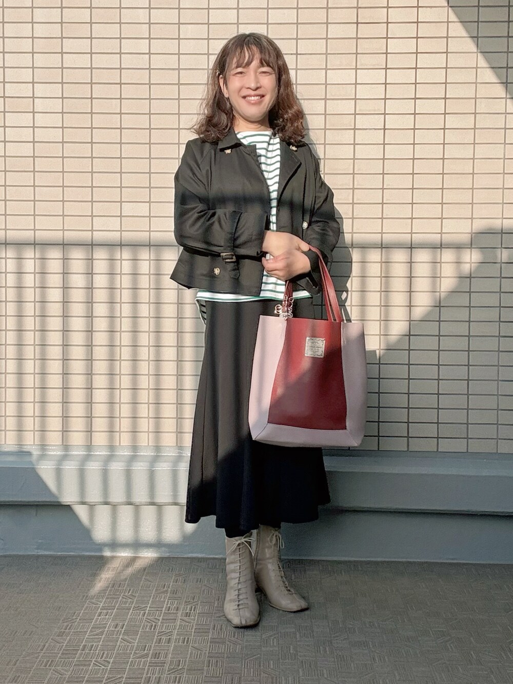 ベージュ系のブーツ、ブラック系のスカート、グリーン系のTシャツ/カットソーを着用したレディースの春コーディネートの2枚目の写真