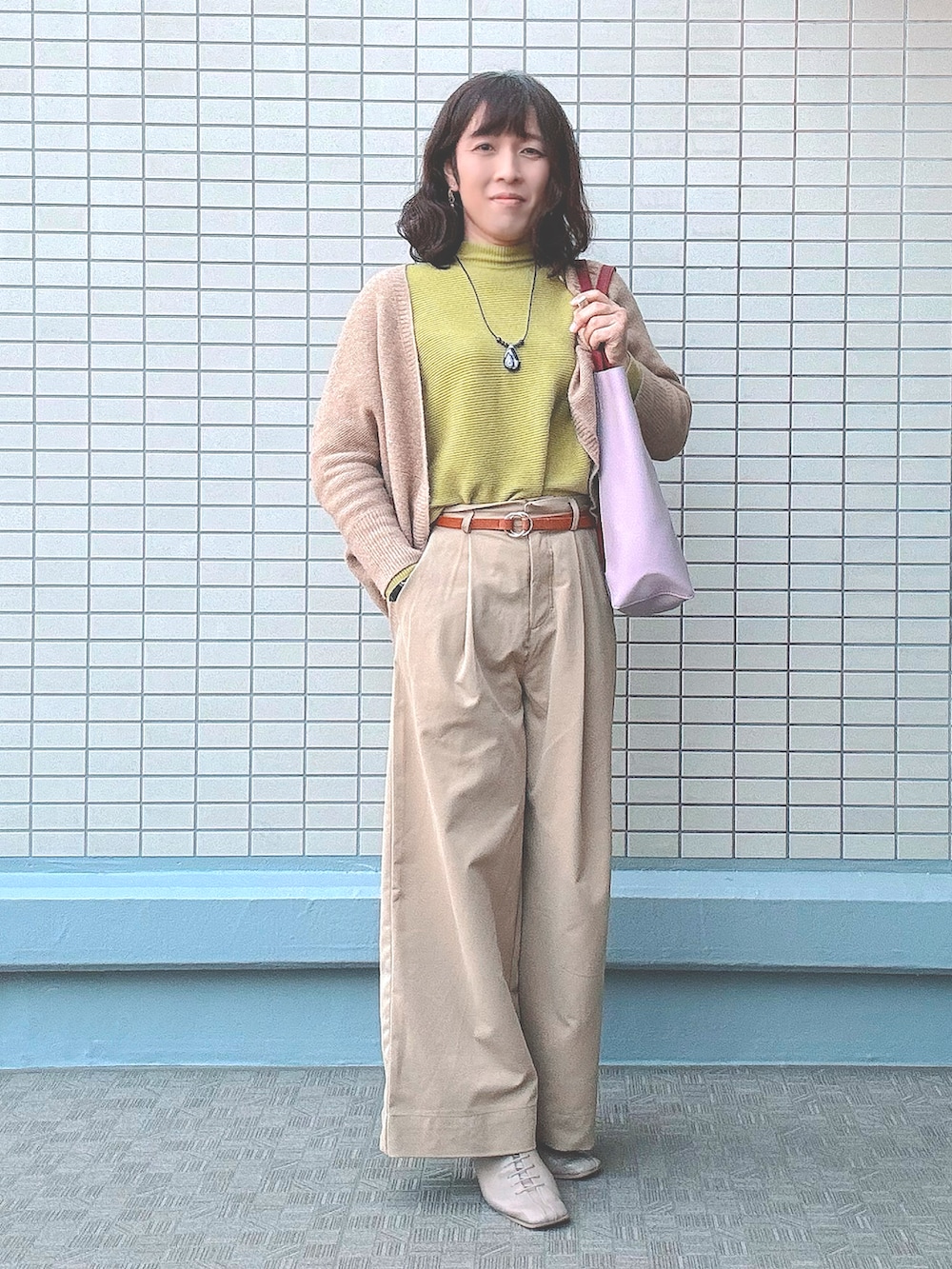 ベージュ系のチノパンツ、ベージュ系のブーツ、レッド系のトートバッグを着用したレディースの冬コーディネートの2枚目の写真