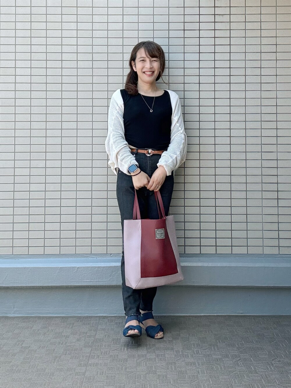 ブルー系のサンダル、ブラック系のデニムパンツ、レッド系のトートバッグを着用したレディースの夏コーディネートの2枚目の写真