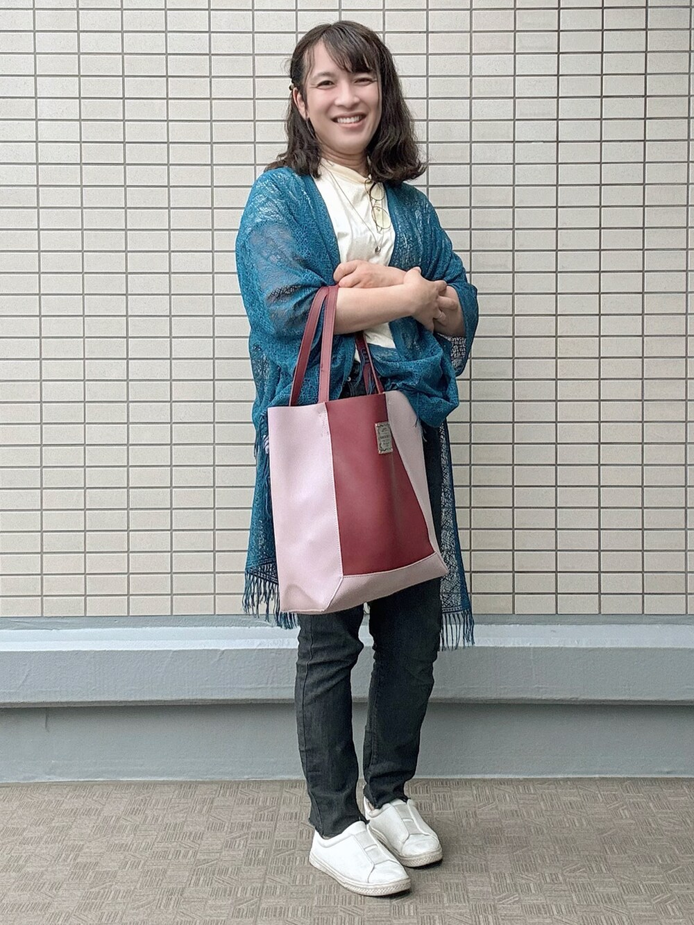 ホワイト系のスニーカー、ブラック系のデニムパンツ、レッド系のトートバッグを着用したレディースの春コーディネートの2枚目の写真