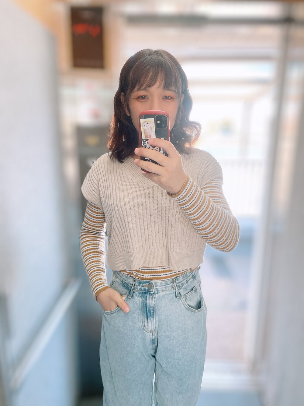 ブルー系のデニムパンツ、ベージュ系のブーツ、ホワイト系のベストを着用したレディースの冬コーディネートの3枚目の写真